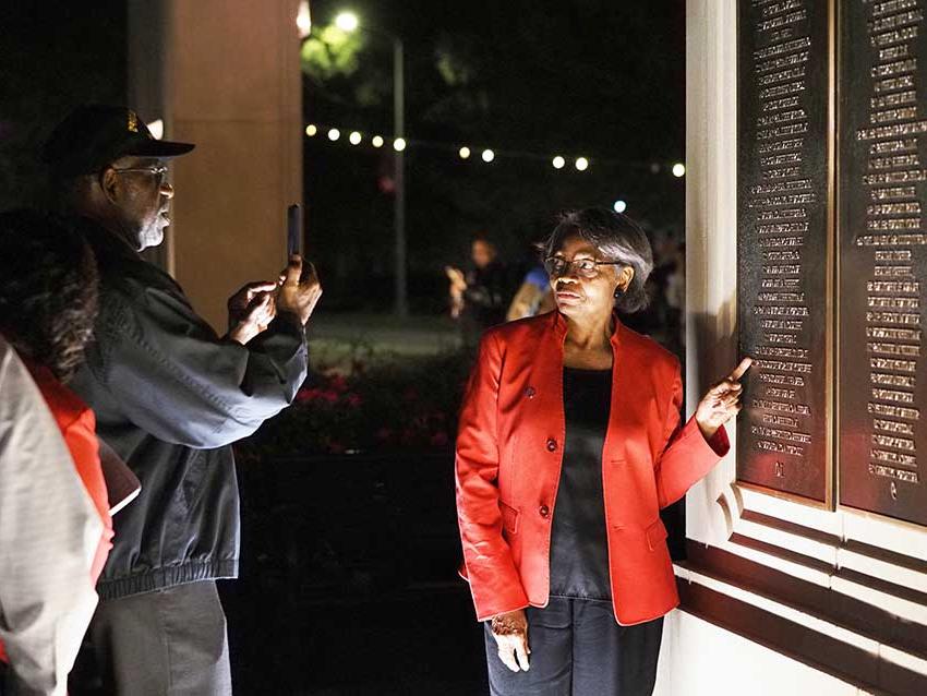 Woman pointing at wall of honor.