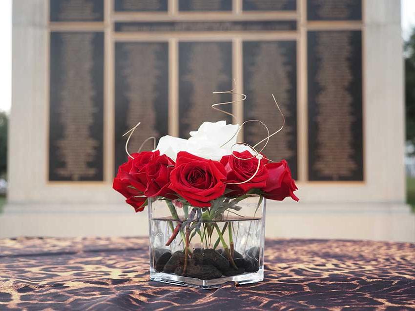 Flowers on table in front of Wall of Honor.